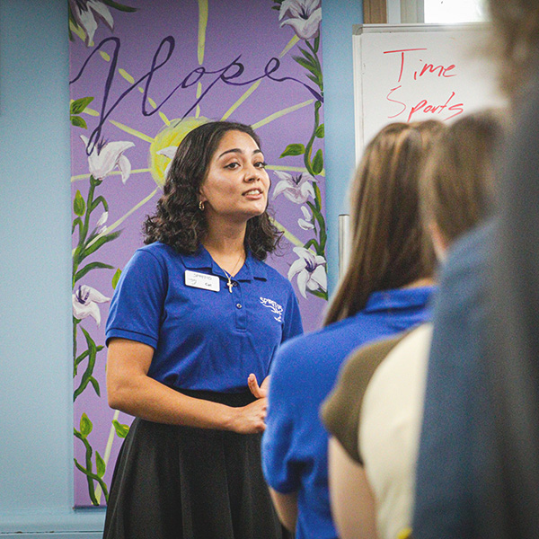 a young woman speaking to a group of young people