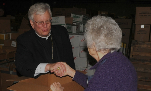 Bishop Ricken speaks with and holds the hand of an elderly woman comforting her