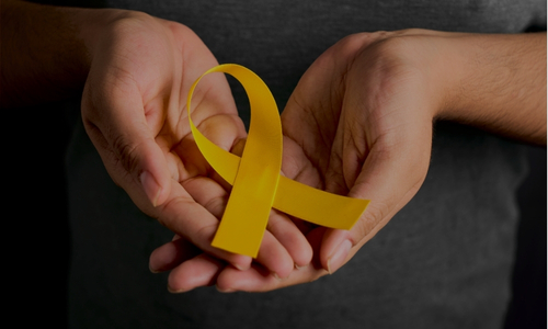 a person's hands hold out a yellow ribbon
